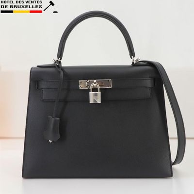 un gros plan d'un sac à main noir posé sur une table blanche