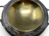 a metal bowl with a handle on a white surface