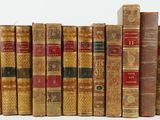 several old books are lined up in a row on a white surface