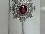 collier en argent orné d'une pierre rouge entourée de diamants sur un support