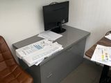 a desk with a computer and a chair in the corner