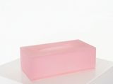 un savon rose posé sur une surface blanche