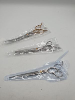trois paires de ciseaux sont emballées dans du plastique sur une surface blanche