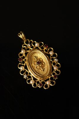 a close up of a gold pendant on a black surface