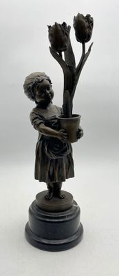 a bronze statue of a boy holding a pot of flowers