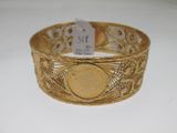 Gros plan sur un bracelet en or orné d'une pièce de monnaie
