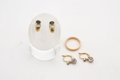 deux bagues en or et une paire de boucles d'oreilles posées sur une table blanche