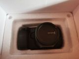 a black camera in a white box with a black lens