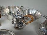 a silver tea pot and other silverware on a table