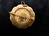 an image of a gold pendant with a woman ' s face on it