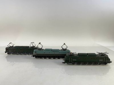 Trois petits trains sont posés sur une surface blanche, devant un fond blanc.