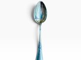 a silver spoon with a blue handle on a white surface