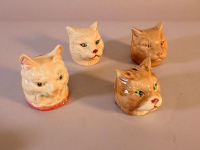 four ceramic cats sitting on top of a white table next to each other
