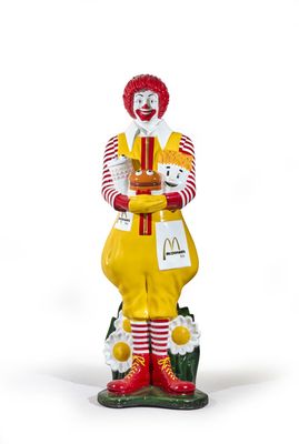 statue of a clown holding a plate of food in his hands