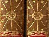 two old books sitting on top of a white table next to each other