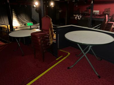 des tables et des chaises dans une salle avec une scène en arrière-plan
