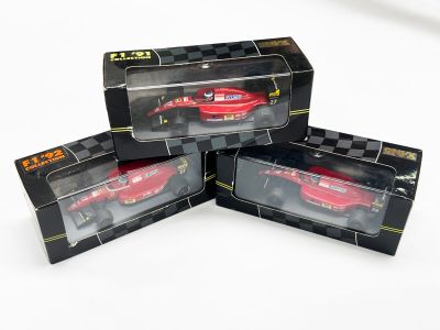 trois voitures rouges se trouvent dans une boîte noire posée sur une surface blanche