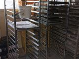 a man standing next to a rack of trays in a kitchen