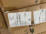 une boîte sur laquelle est collée une étiquette de prix, posée sur une pile de boîtes