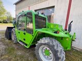 a green tractor parked in front of a building next to a building