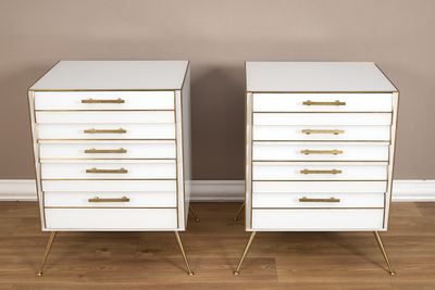 une paire de tables de chevet blanches et dorées avec des poignées en laiton