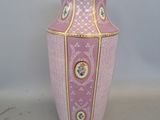 un vase rose orné d'une bordure dorée, posé sur une surface blanche
