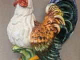 un coq en céramique posé sur une plante