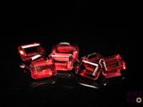 quatre perles cubiques en verre rouge sur un fond noir