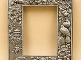 un cadre photo en métal orné d'oiseaux et de fleurs sur fond beige