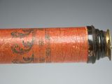 a close up of a red cylinder with a black and gold design on it