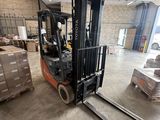 un chariot élévateur dans un entrepôt où se trouvent des palettes et des cartons
