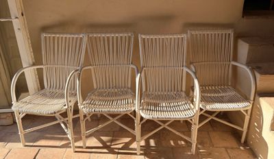 trois chaises en osier blanc disposées sur une terrasse, près d'un mur