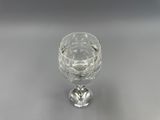 une image représentant un verre à vin en cristal posé sur une surface argentée