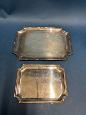 two silver trays with handles and handles on a blue background