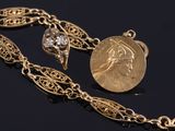 a close up of a gold necklace with a coin on it