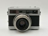 a silver camera with a black lens on a white surface