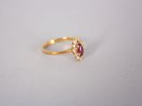 une bague en or sertie d'un rubis ovale entouré de petits diamants blancs