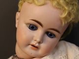 a close up of a doll with blonde hair and blue eyes