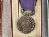 two medals are in a box on a table next to a pair of scissors