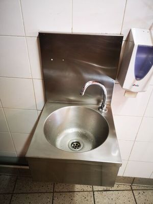 un évier en acier inoxydable dans le coin d'une toilette publique
