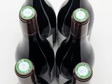 six bottles of wine are lined up in a row on a white surface