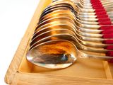 plusieurs cuillères et un repose-cuillères dans une boîte en bois rayée de rouge et de blanc