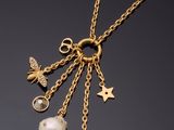 un gros plan sur un collier plaqué or orné de perles et de breloques