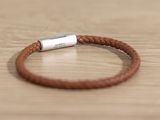 brown leather bracelet with a silver clasp on a wooden table