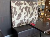 tables and benches in a restaurant with a cow print wall