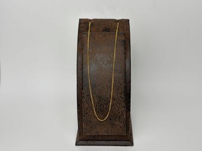 présentoir à bijoux en bois avec une chaîne dorée sur fond blanc