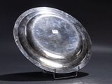 a silver plate sitting on a stand on a black surface
