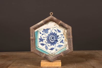 un petit carreau bleu et blanc posé sur un socle en bois