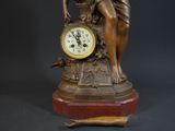 a statue of a woman holding a clock on a table