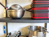 de nombreuses casseroles et poêles sur les étagères de la cuisine